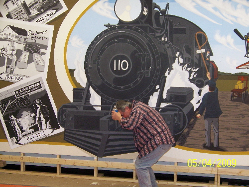 Pat wonders if he made the train too real.  He used the single vanishing point perspective.  When you look at the mural and walk from one side to the other it looks like the train follows you.